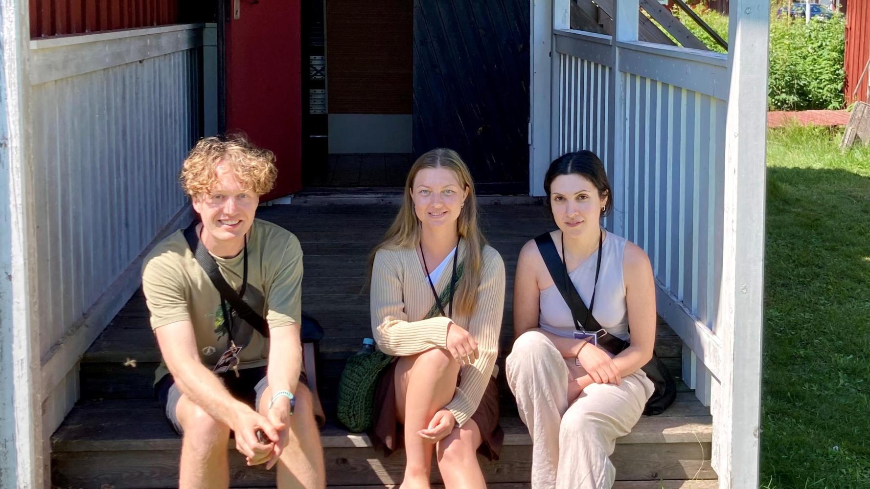 Tre sommarklädda ungdomar på en trappa