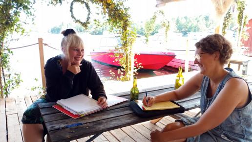 Två kvinnor samtal om ett manus i skärgårdsmiljö
