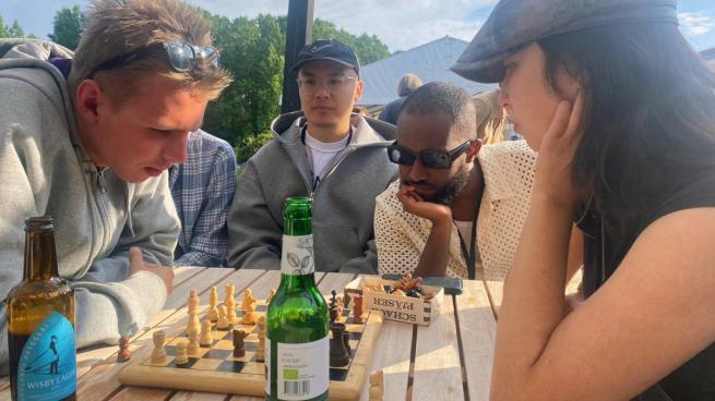 Two people playing chess, with two watching