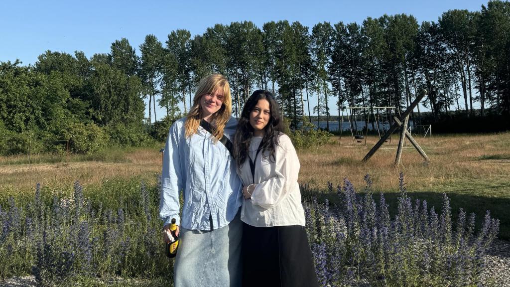 två kvinnor framför fårölandskap