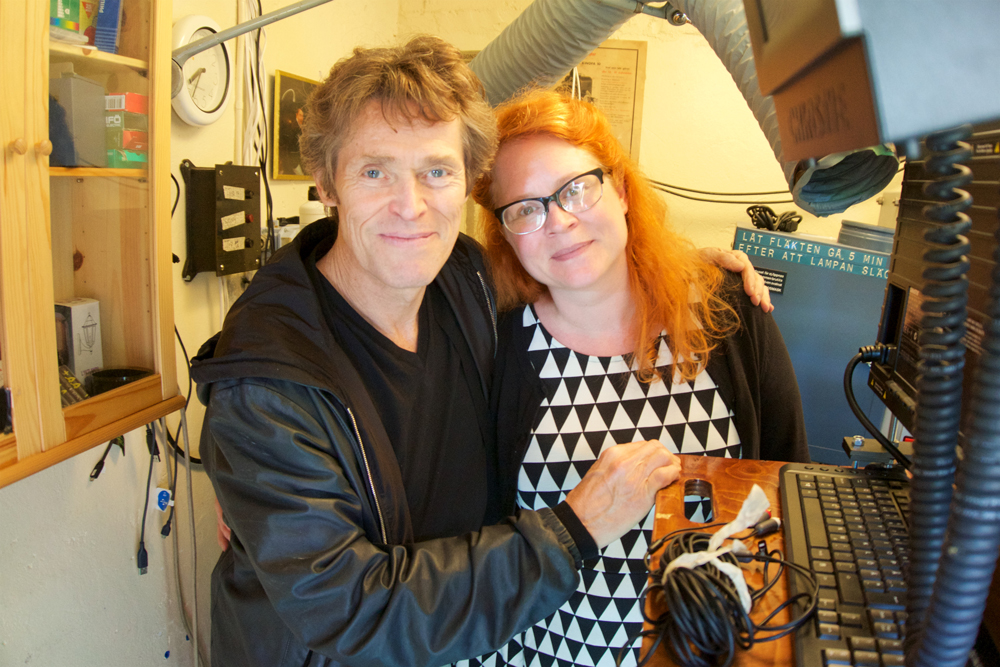 Biografmaskinisten Åsa Hoflin drar biografens historia för den nyfikna Willem Dafoe. Hon berättar att det tidigare varit en lada för grisar och att Bergman och Sven Nykvist såg sina dagstagningar där under inspelningen av ”Så som i en spegel” (Förra årets biografmaskinist sa att det var kor i ladan. Men det spelar kanske ingen roll?) Foto: Martin Hammar