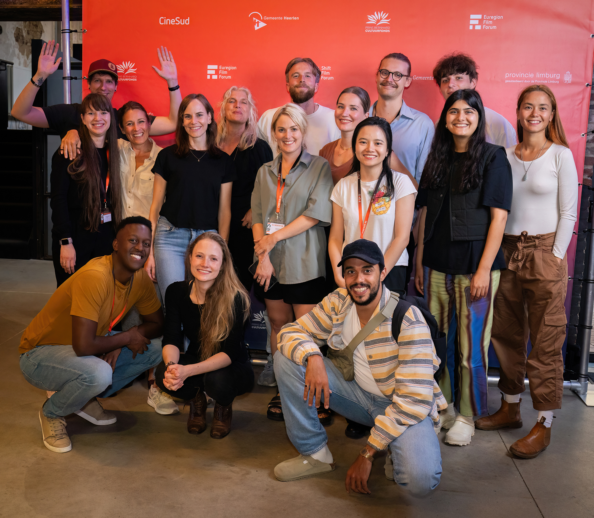 Grupp med unga människor framför fotoduk med festivalloggor.