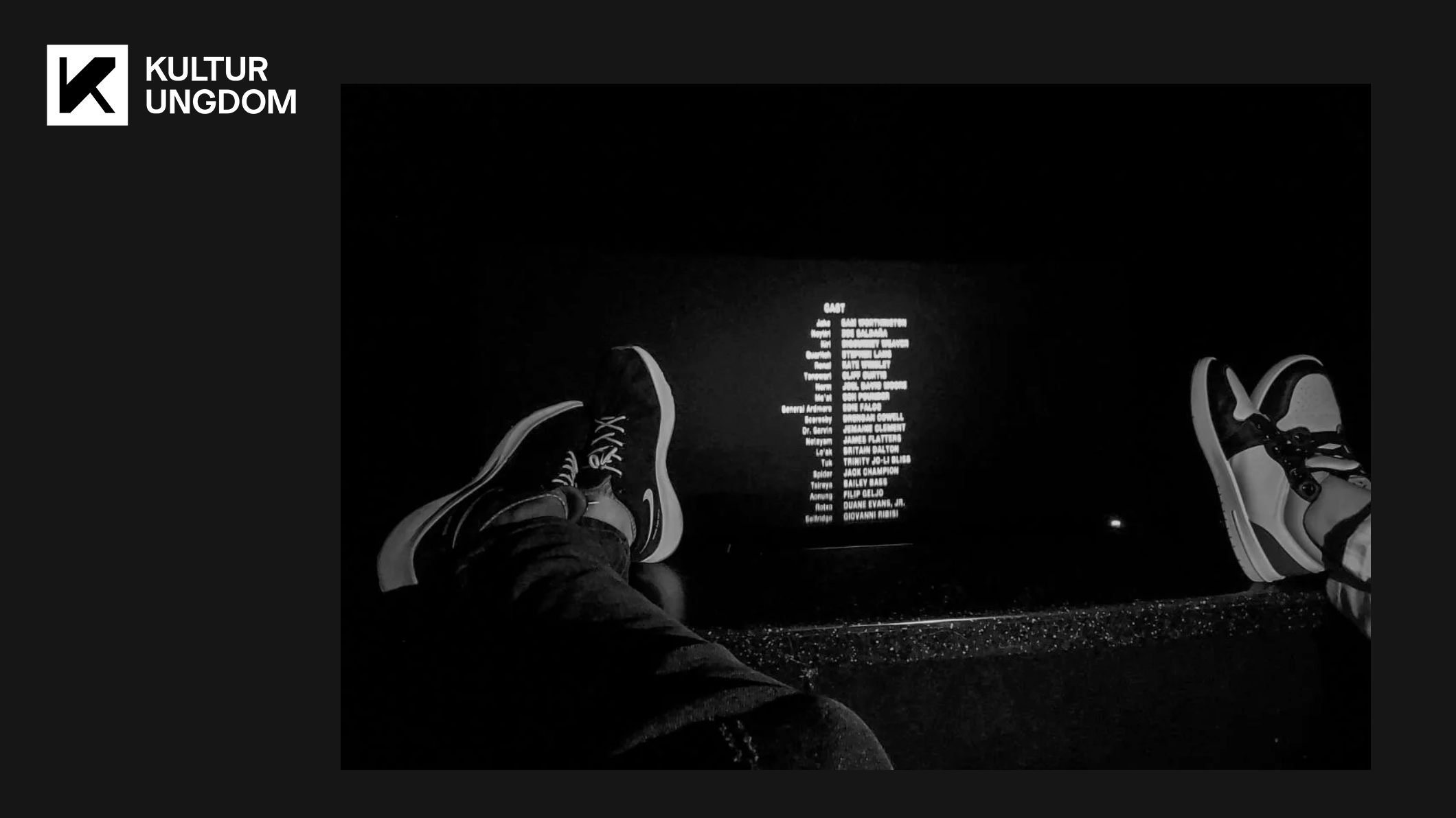 Fötter på biografens stolsryggar och eftertexter i bakgrunden