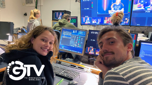 En kille och en tjej som sitter framför dator och tittar tillbaka mot kameran