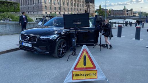 svart bil framför kungliga slotte och en skylt där det står filminspelning