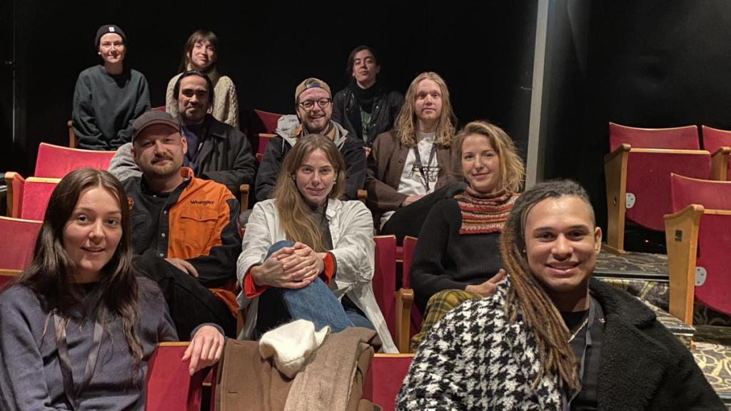 11 personer i biograffåtöljer ler mot kameran.